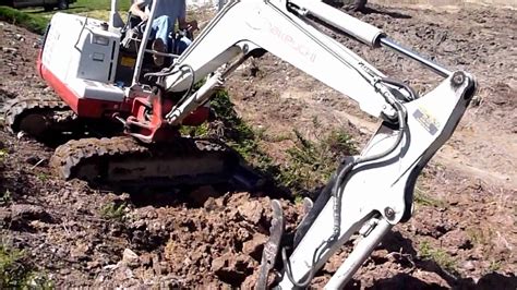 mini excavator trenching across a slope|mini digger steep slope.